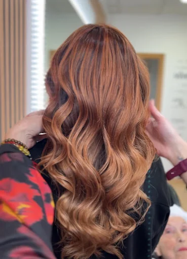 Mechas cobrizas con ondas y degradado cálido en Salón Aurora Montilla